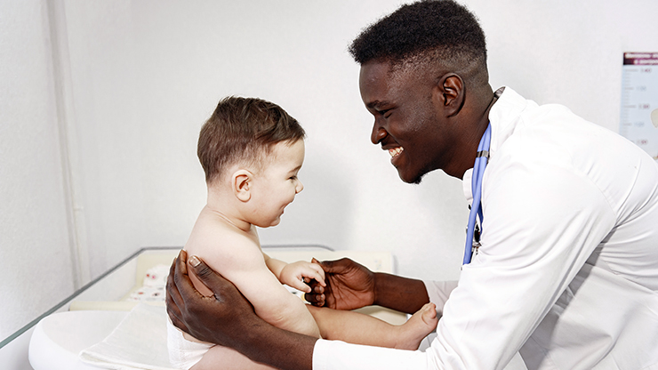 African doctor examines a little boy on couch